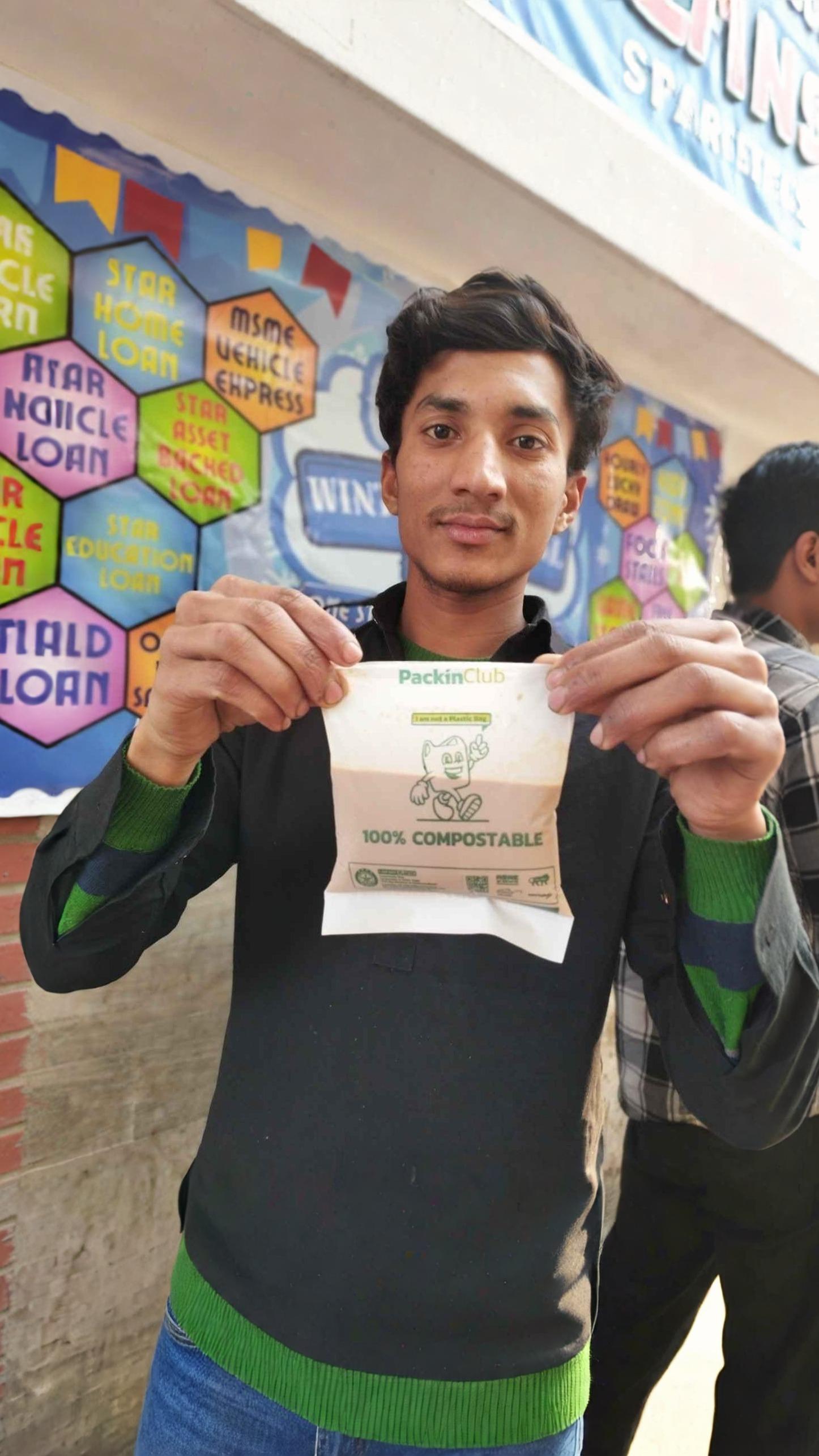 Individual holding a Packin Club certified compostable packaging bag designed as an environmentally responsible alternative to conventional plastic packaging.